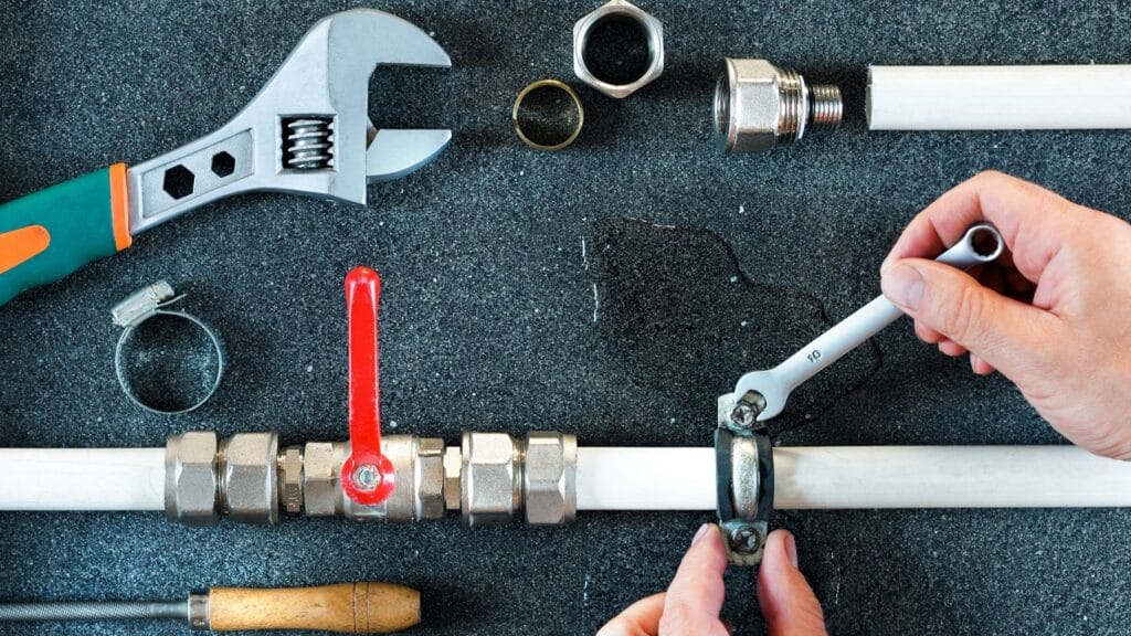 Plumber repairing a pipe valve with an adjustable wrench in Margate
