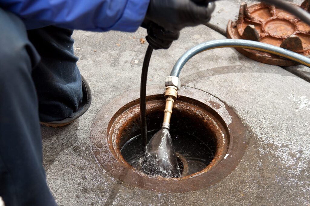 Plumber hydro jetting a sewer line through a manhole in Margate