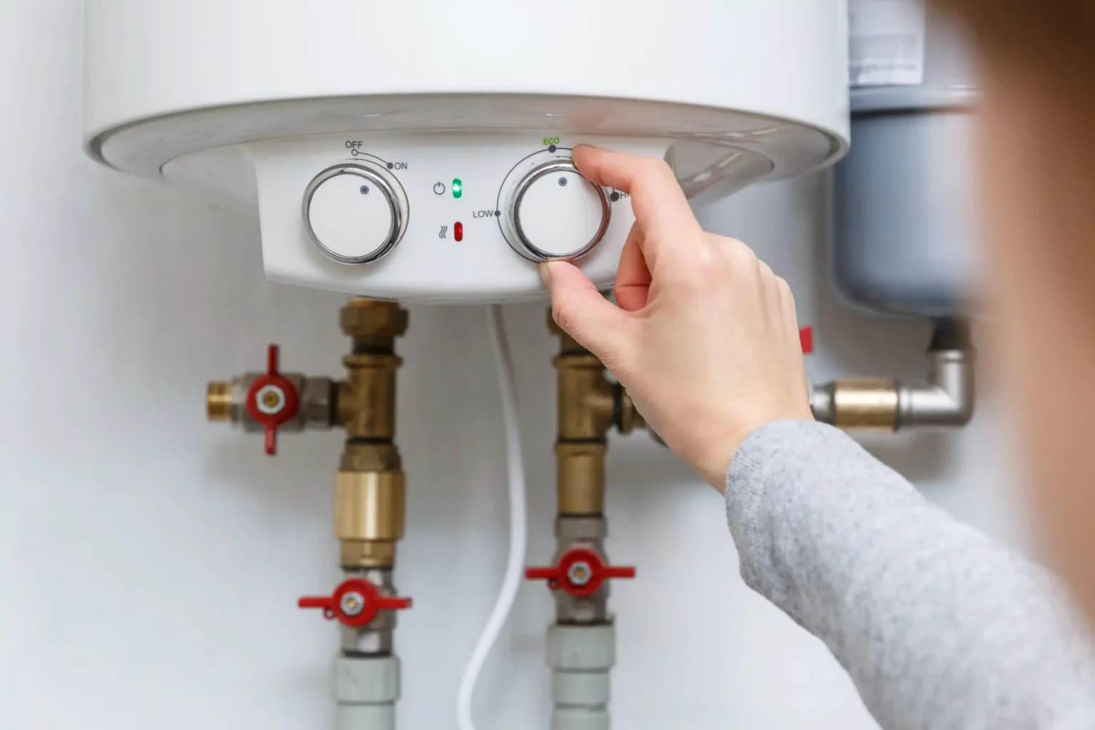 Homeowner adjusting the temperature controls on a water heater in Margate